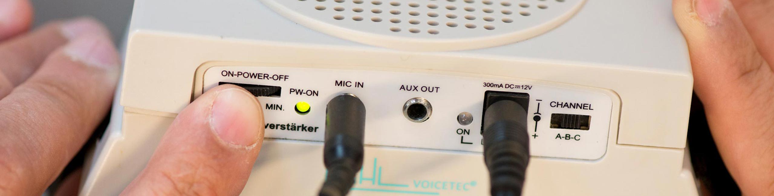 Ein Audioverstärker mit verschiedenen Einstellungen und Audio Ein- und Ausgängen. Jemand dreht gerade die Lautstärke hoch.