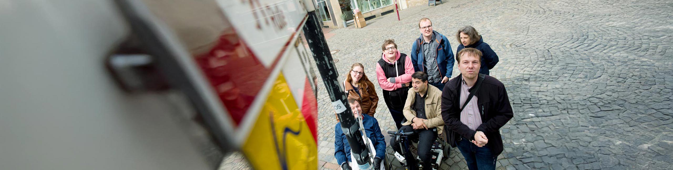 Das Team vom Büro für Leichte Sprache ist in einer Stadt unterwegs. Alle 7 Personen lächeln in die Kamera.